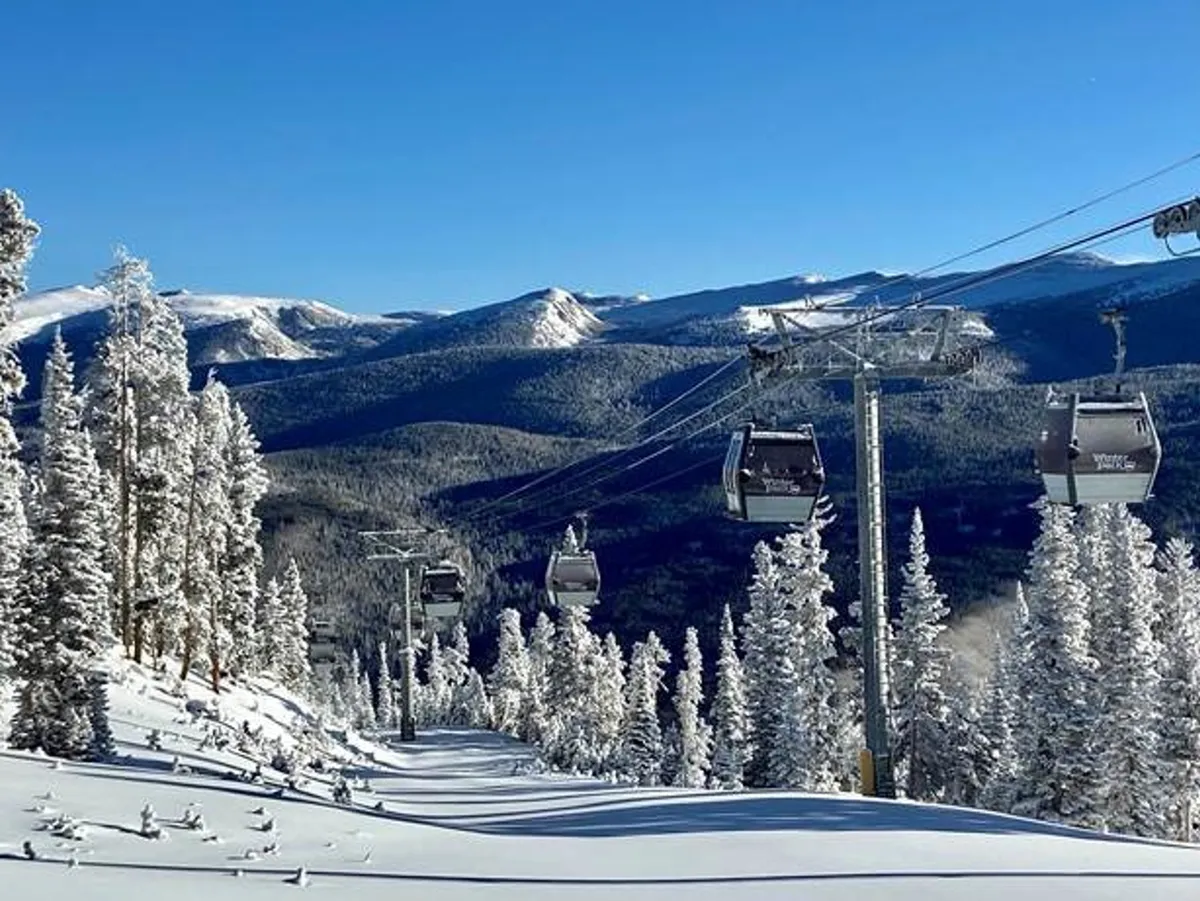 A dramatic exterior shot of ski lift gondolas gliding above snow-covered trees and a mountainous landscape, capturing the sense of adventure and the natural beauty just outside the property.